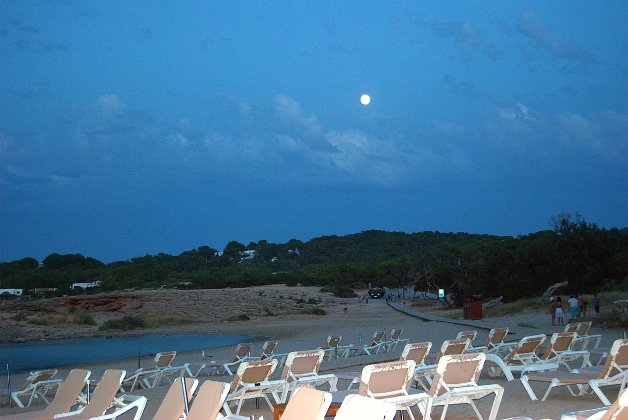 Mond über den leeren Liegen von Cala Bassa in der Abenddämmerung