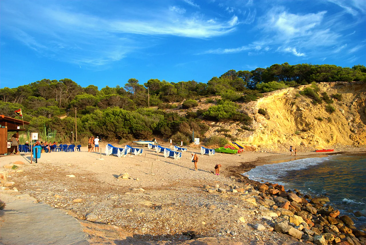 Strand Cala Codolar mit blauen Liegen unter der Steilküste