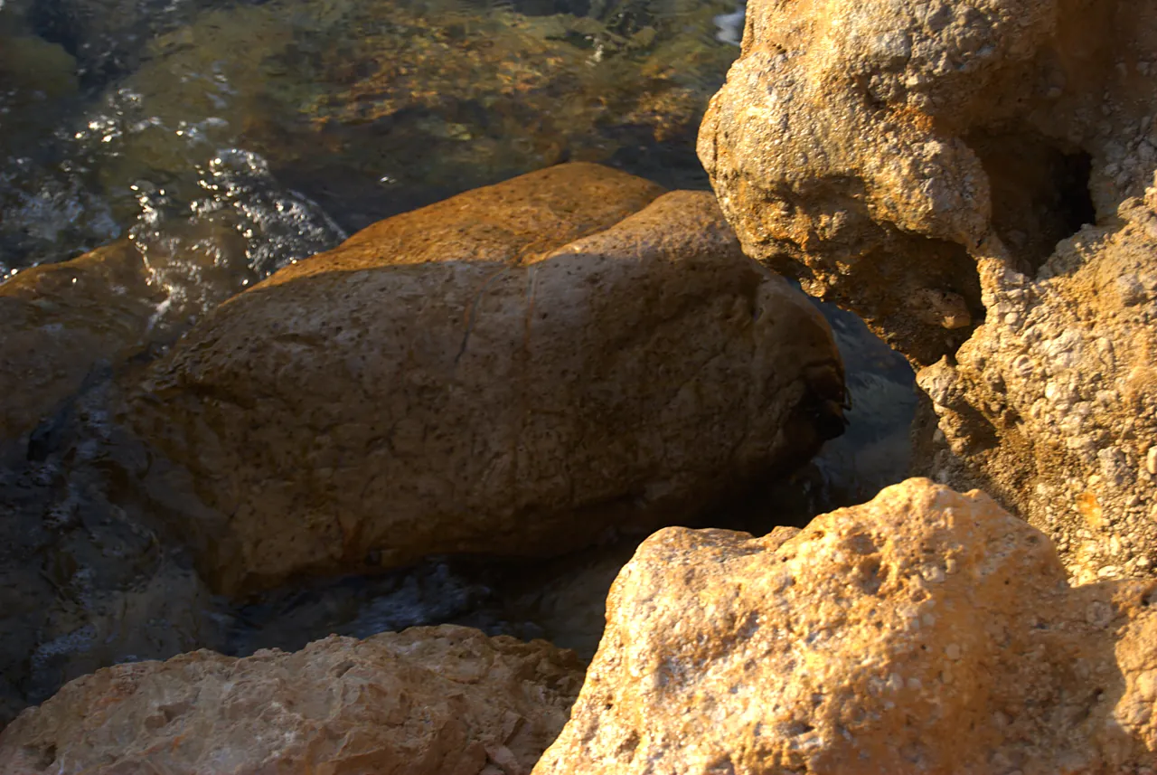 Von der Sonne vergoldete Felsen am Wasser der Cala Codolar