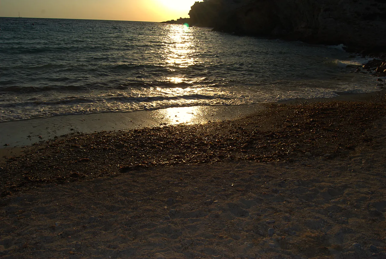 Die untergehende Sonne spiegelt sich im Meer der Cala Codolar