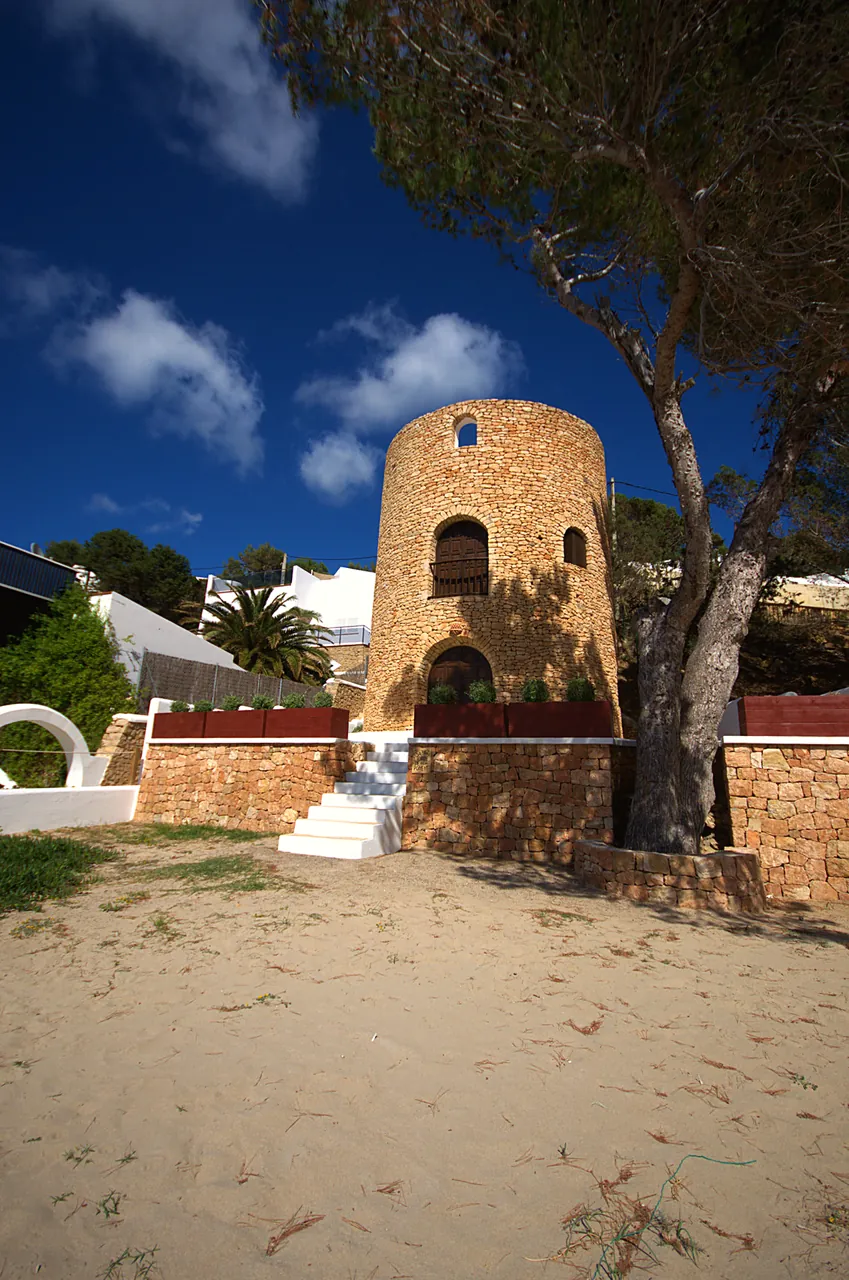 Cala Vadella 9 Torre de piedra entre pinos junto a la arena de Cala Vadella