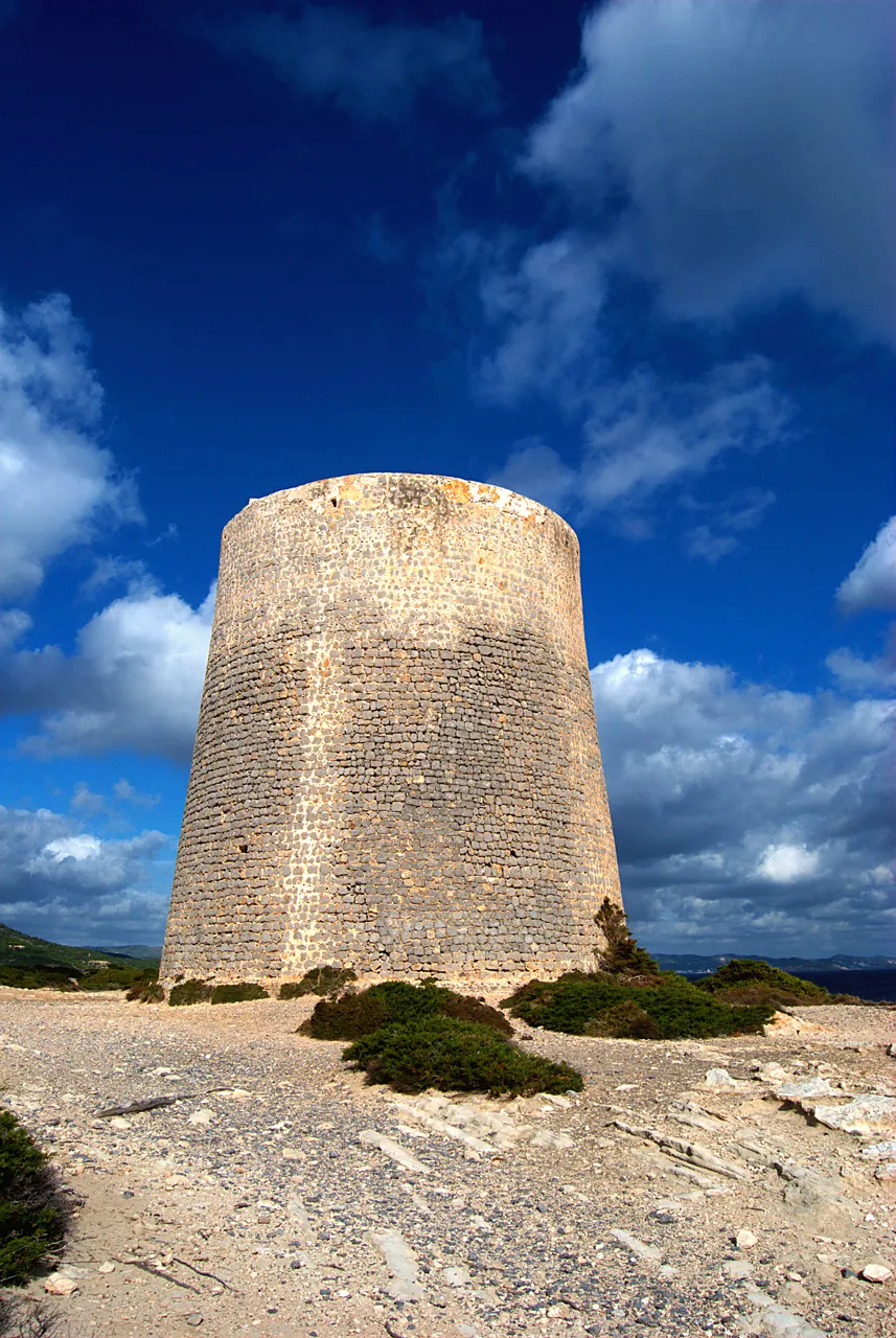 Torre de ses Portes sobre las rocas bajo un cielo de nubes