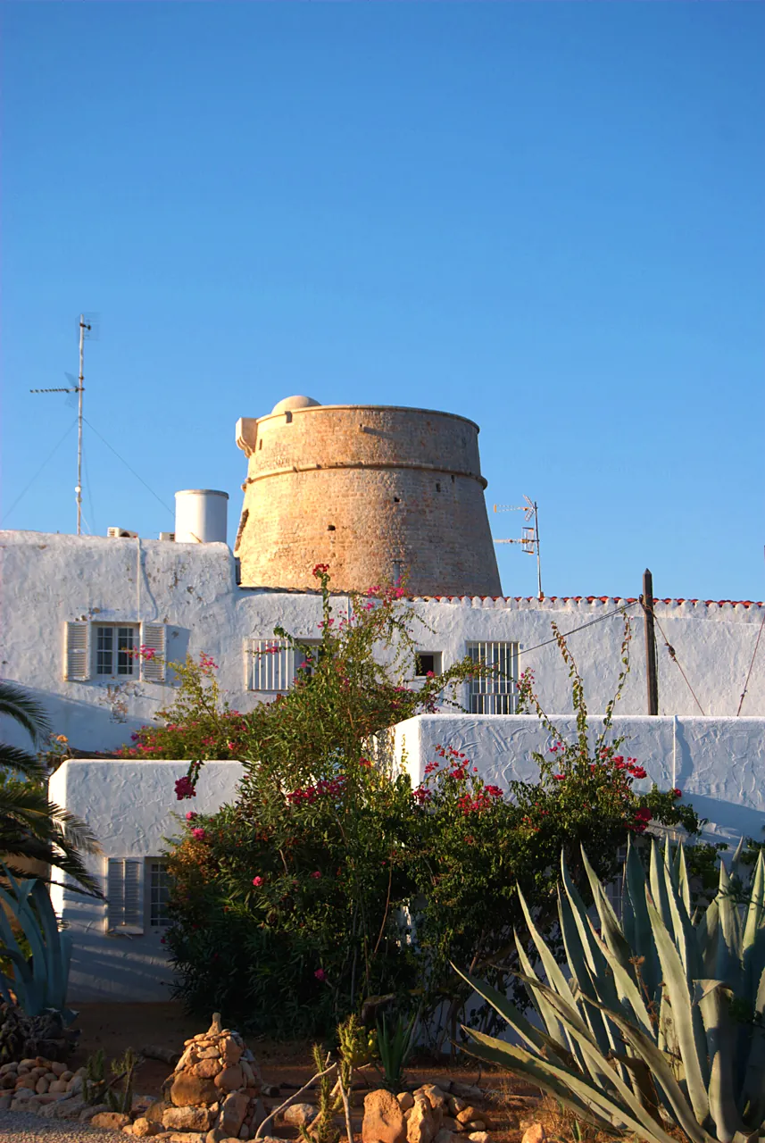 Torre de sa Sal Rossa sobre una casa encalada con pitas